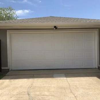 White paneled garage door on residential home with concrete driveway.